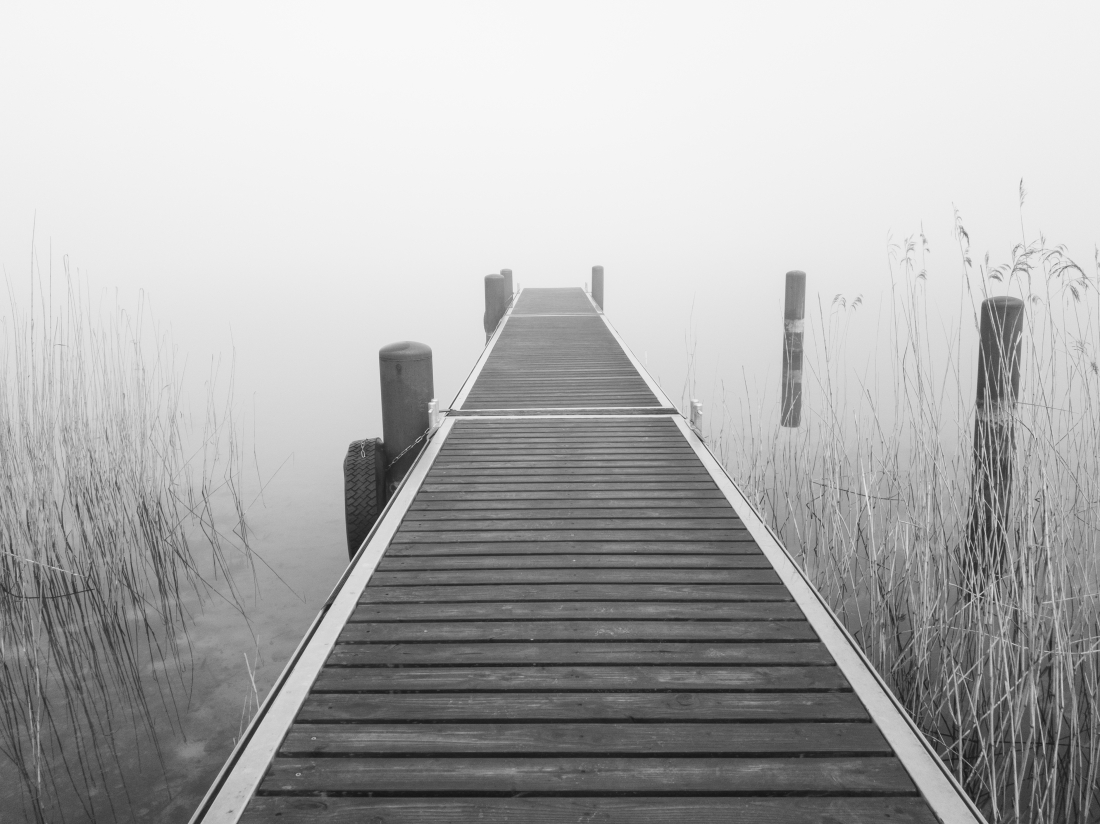 The jetty on the foggy lake, in shades of grey